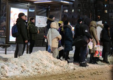  İnsanlar otobüs durağında bekliyor. Kış gecesi yolda kar yağıyor.