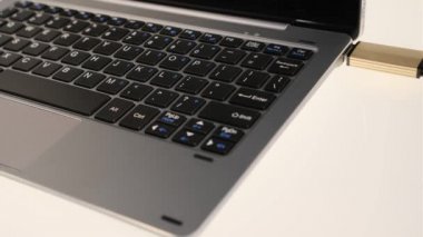 Hacker USB çubuğundaki verileri ekler ve kopyalar, sonra da siyah eldivenlerle dizüstü bilgisayara yazar.