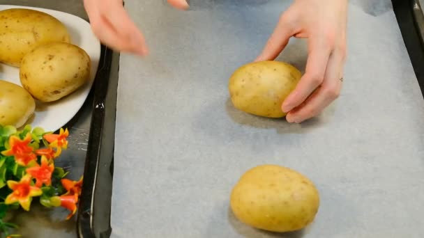 Het plaatsen van hele rauwe aardappelen op ovenschaal voor het bakken — Stockvideo