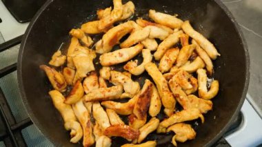 sarımsaklı tavuk göğsü eti ve yağlı ve baharatlı ahşap kaşıkla karıştırılıyor.