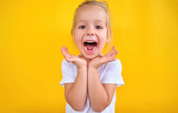 Sarı arka planda izole edilmiş, mutlu, küçük bir kız gülümsüyor. Yüksek kalite fotoğraf