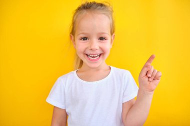 Smiling preschool girl showing , pointing at copy space for advertising text, big sale announce