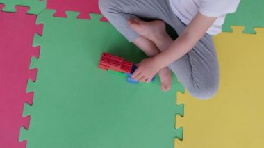 Küçük kız lego inşaatçısını parçalara ayırıyor oyuncakları tuğlalıyor ve ön tarafa yerleştiriyor.