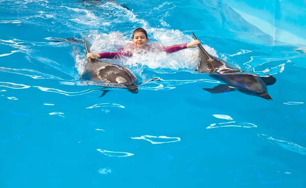Criança montando em golfinhos — Fotografia de Stock