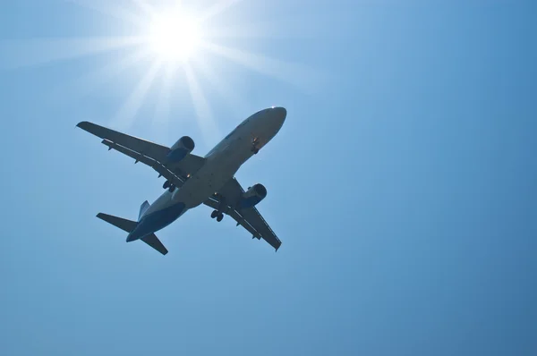Avião de passageiros silhueta contra sol brilhante — Fotografia de Stock