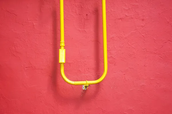 红色背景上的黄色管 — 图库照片