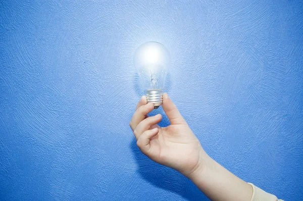 Glowing lamp in hand on blue background — Stock Photo, Image