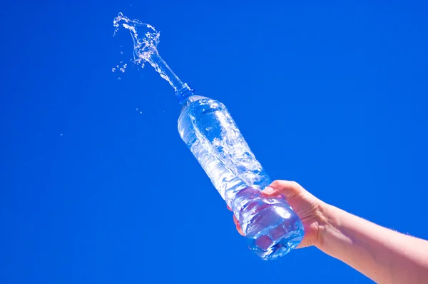 Eau pure éclaboussures de bouteille contre le ciel bleu — Photo