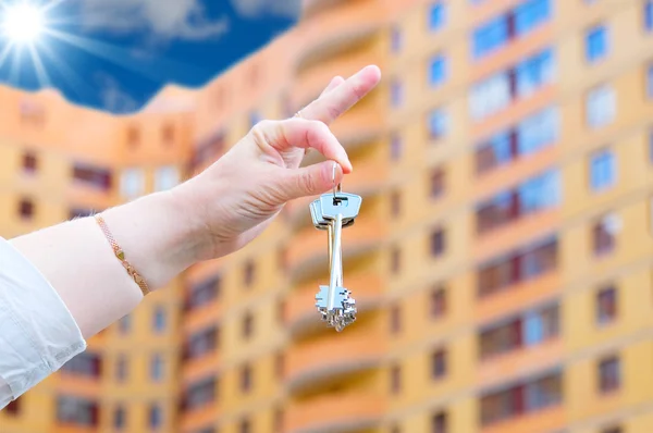 Hand holding keys on new house background — Stock Photo, Image