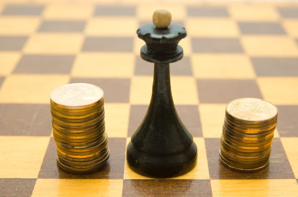 Шахматная дама и монеты на шахматной доске — стоковое фото