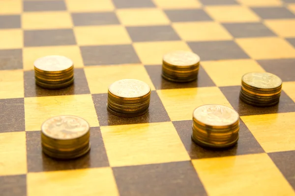 Монеты на шахматной доске — стоковое фото