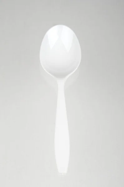 Cucchiaio di plastica su sfondo grigio — Foto Stock