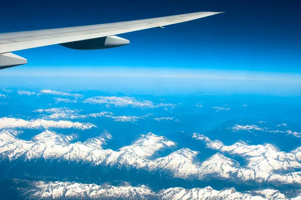 Snow-capped mountains under plane wing — Stock Photo, Image