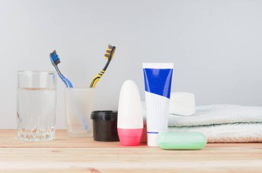 Su bardağı, macun, sabun ve havluyla ahşap zemin üzerinde diş fırçaları