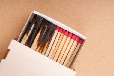 Matchbox with matches and burnt matches on brown background