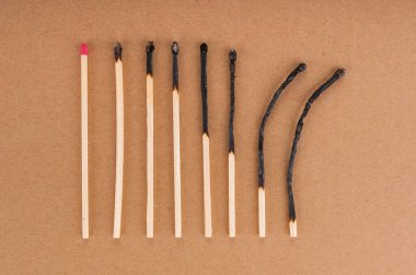 Row of different burnt matches on brown background