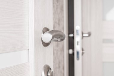 Metallic door handle on a wooden door close up