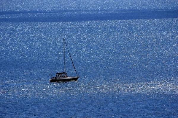 Båt till sjöss. En ensam segelbåt i det blå havet — Stockfoto