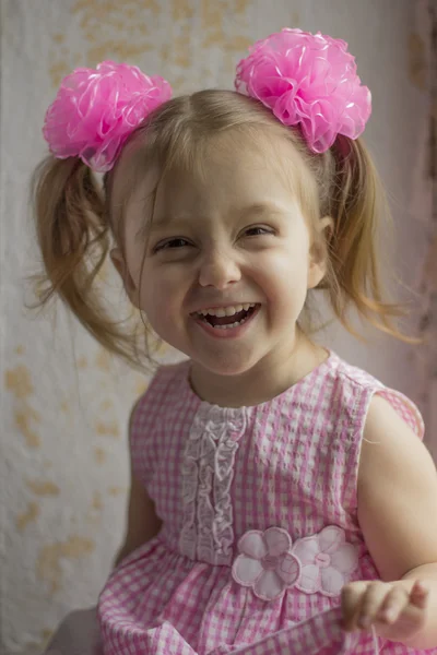 Skrattande liten unge. Lycklig liten flicka 3-4 år gammal på bakgrunden av den gamla muren — Stockfoto
