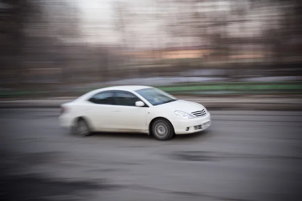 Κίνηση αυτοκινήτου. Το λευκό αυτοκίνητο ξεπερνά την ταχύτητα του δρόμου της πόλης — Φωτογραφία Αρχείου