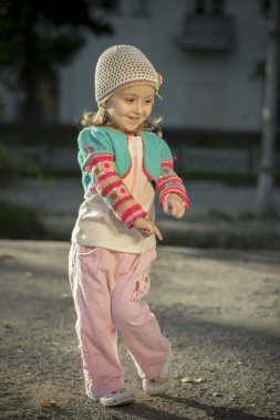 Sarı saçlı dansları sıcak güneşli bir parkta küçük neşeli kız