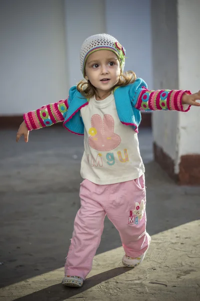 Pequena menina feliz bonito em um parque corre, braços estendidos, desfrutando de liberdade — Fotografia de Stock