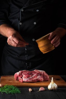 Profesyonel şef ete tuz serpiyor. Pişirmeden önce et hazırlıyorum. Bir restoranın mutfağında çalışma ortamı