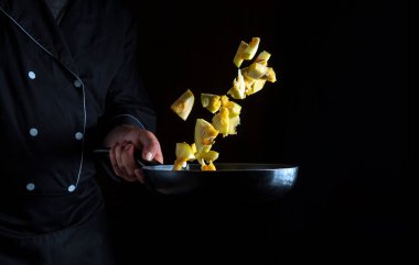 Aşçı kabağı tavada hazırlar. Sebze pişirmek sağlıklı vejetaryen yiyecekler ve karanlık arka planda yemek. Boş reklam alanı