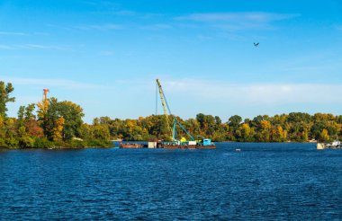Nehir boyunca adaya giden bir köprü inşaatı başlıyor. Vinçli bir gölette mühendislik işi.