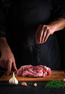 Aşçı ete tuz serper. Pişirmeden önce et hazırlıyorum. Bir restoranın mutfağında çalışma ortamı