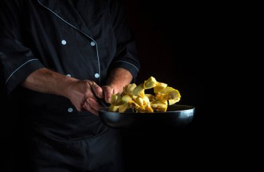 Şef bir tavada kabak hazırlar. Sebze pişirmek sağlıklı vejetaryen yiyecekler ve karanlık arka planda yemek. Ücretsiz reklam alanı