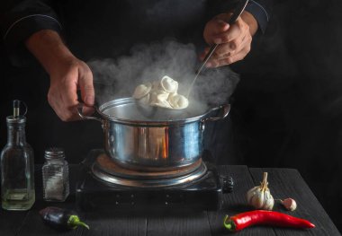 Profesyonel şef, restoranın mutfağındaki bir tencerede köfte pişiriyor. İş sırasında aşçının ellerini yakın plan çek.