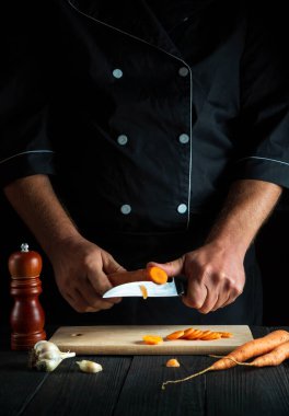 Aşçı restoran mutfağında sebze çorbası için havuç kesiyor. İş sırasında şefin ellerini yakın plan çek. Havuç diyeti