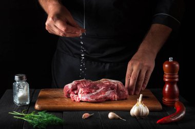 Profesyonel şef ete tuz serpiyor. Pişirmeden önce et hazırlıyorum. Restoranın mutfağında çalışma ortamı