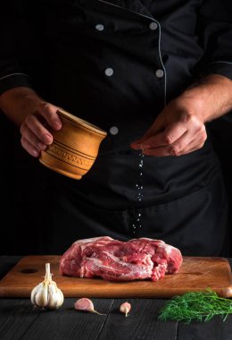 Pişirmek et ve tuz serpiyor. Pişirmeden önce et hazırlıyorum. Bir restoranın mutfağında çalışma ortamı