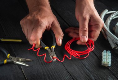 Ustabaşı çalışırken ya da kırmızı kabloyu keserken elektrikçinin yakın çekimleri. Profesyonel elektrikçinin atölyesinde elektrik teçhizatı tamiri