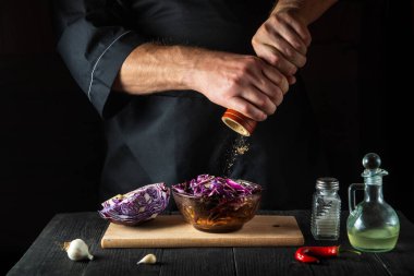 Şef taze kırmızı lahana salatasına biber ekler. Lokanta mutfağında sağlıklı yemekler pişirmek..
