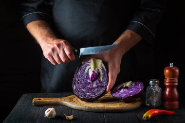 Aşçı bir bıçakla kırmızı lahana kesiyor. Restoranın mutfağında sebze salatası pişiriyorum. Sebze diyeti fikri