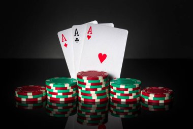 Üçlü ya da set kombinasyonlu poker oyunu. Fişler ve kartlar siyah masada. Başarılı ve üç as kazandı.