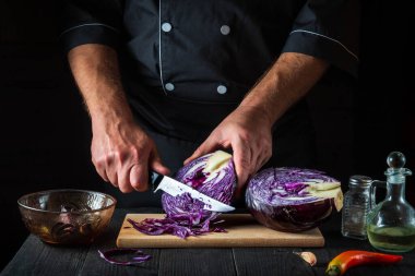 Şef bir bıçakla kırmızı lahana kesiyor. Restoranın mutfağında sebze salatası pişiriyorum. Sebze diyeti fikri.