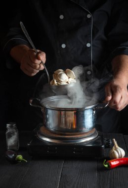 Aşçı, restoranın mutfağındaki tencerede etli börek pişiriyor. İş sırasında aşçının ellerini yakın plan çek.