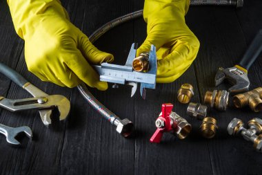 Büyücü ya da usta suyu ya da gaz borusunu bağlamadan önce kalibrenin boyutunu ölçer. Atölyedeki ustanın ellerine yakın çekim