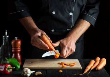 Aşçı bir restoranda sebze çorbası için havuç soyar. İş sırasında şefin yakın çekimleri. Havuç diyeti