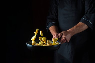 Aşçı kabağı tavada hazırlar. Sebze pişirmek sağlıklı vejetaryen yemekleri ve siyah arka planda yemek