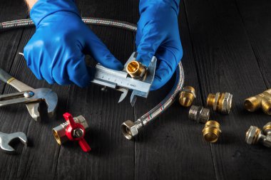 Büyücü, su ya da gaz borusunu bağlamadan önce kalibrenin boyutunu ölçer. Usta muslukçunun yakın çekimi.