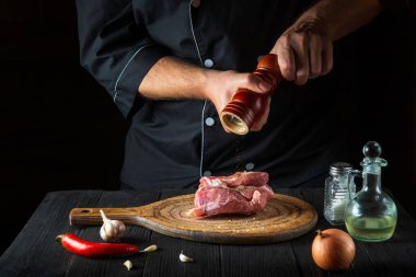 Profesyonel şef çiğ et fileto pişiriyor ve salamura için biber ya da biber ekliyor. Restoranda ya da kafede, mutfakta çalışma ortamı