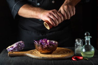 Profesyonel bir şef taze kırmızı lahana salatasına biber ekler. Lokanta mutfağında sağlıklı yemekler pişirmek..