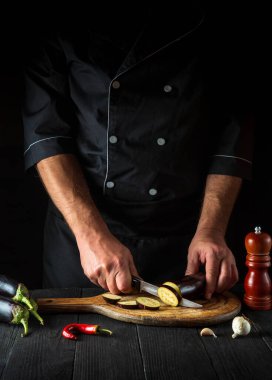 Profesyonel şef restoranın mutfağında patlıcan kesiyor. İş sırasında aşçının ellerini yakın plan çek. Lezzetli kahvaltı ya da akşam yemeği.