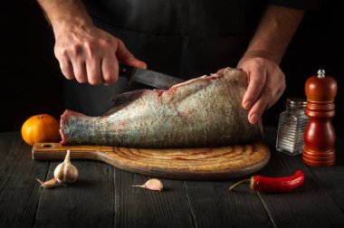 Şef ya da aşçı kocakafalı sazan balığı temizliyor. Restoranın mutfağında çalışma ortamı. Balık diyeti konsepti.