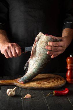 Aşçı pişirmeden önce balığı keser. Restoranın mutfağında çalışma ortamı. Balık diyeti konsepti.